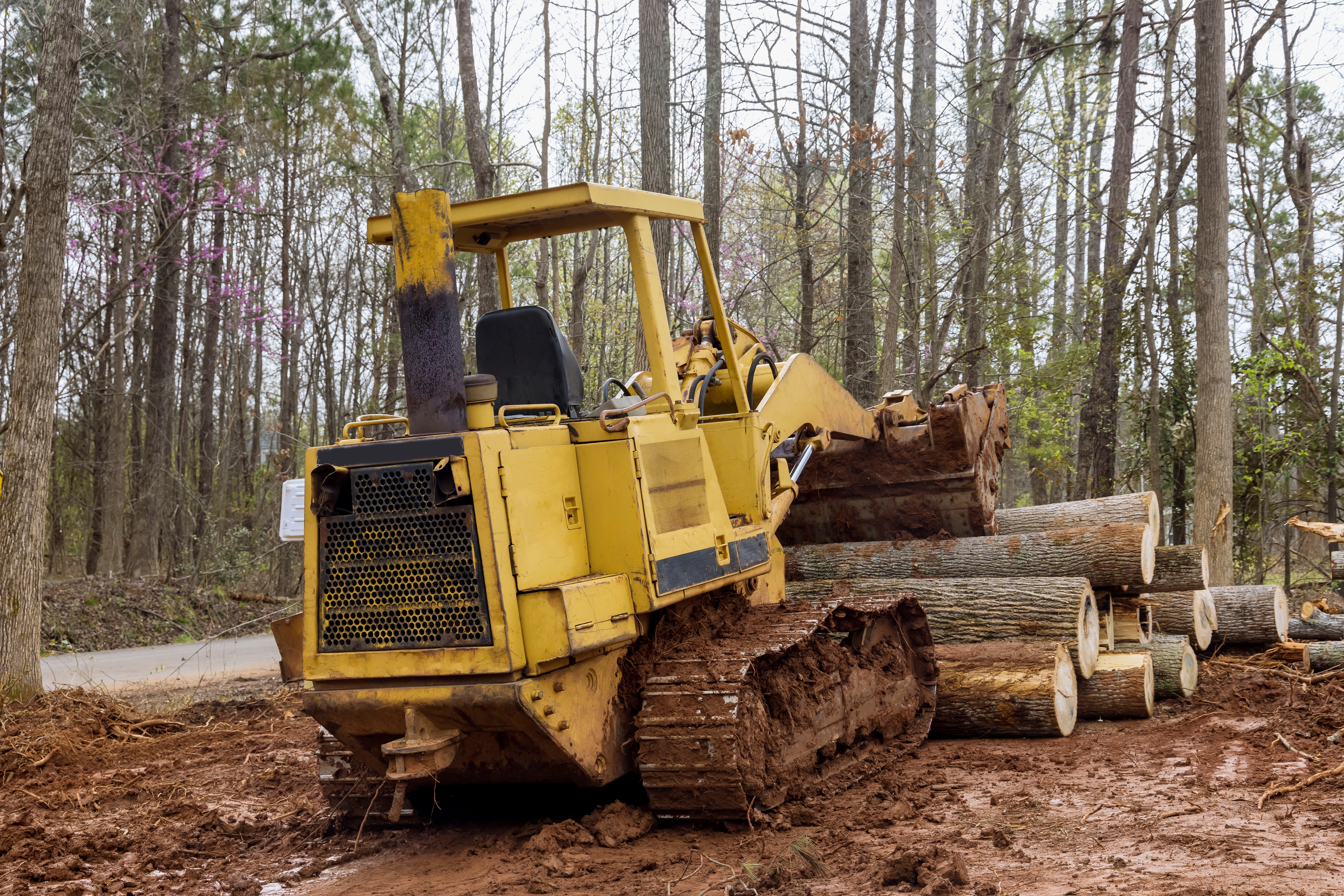 A yellow tractor is parked in the dirt.